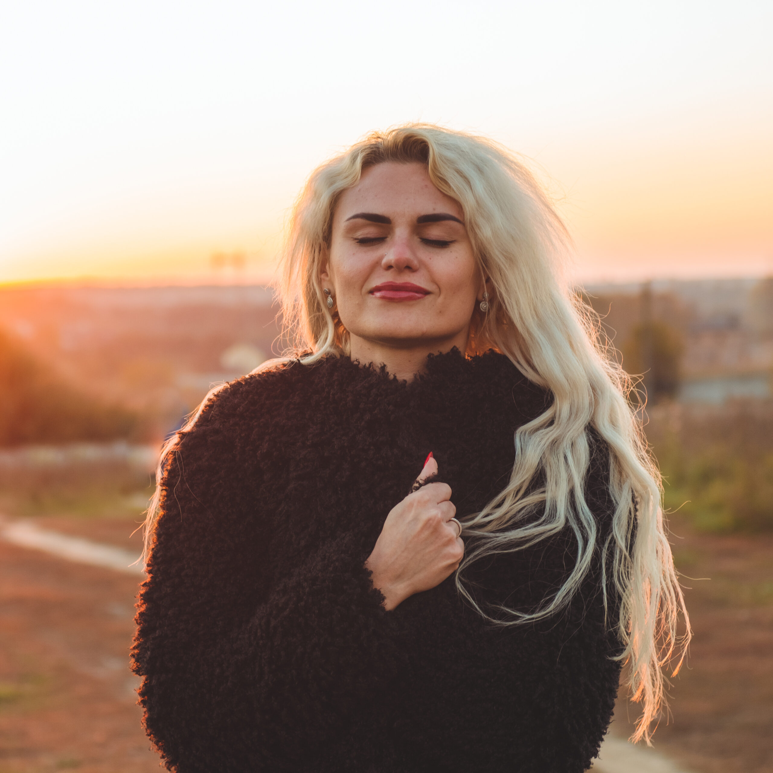 Beauty Romantic Girl Outdoors enjoying nature. Beautiful autumn model with waving glow hair. Sun light on sunset. Portrait of romantic female